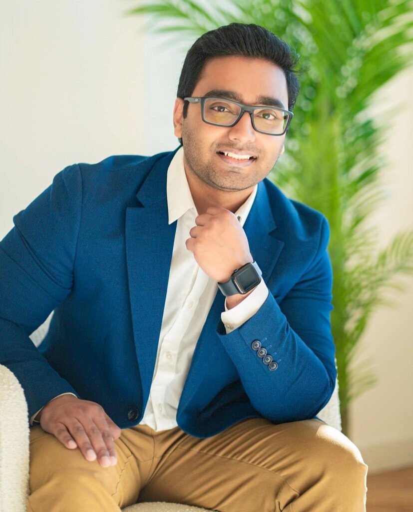 Professional portrait of Mortgage Agent Abhishek, smiling confidently in a blue blazer, seated in a bright modern setting.