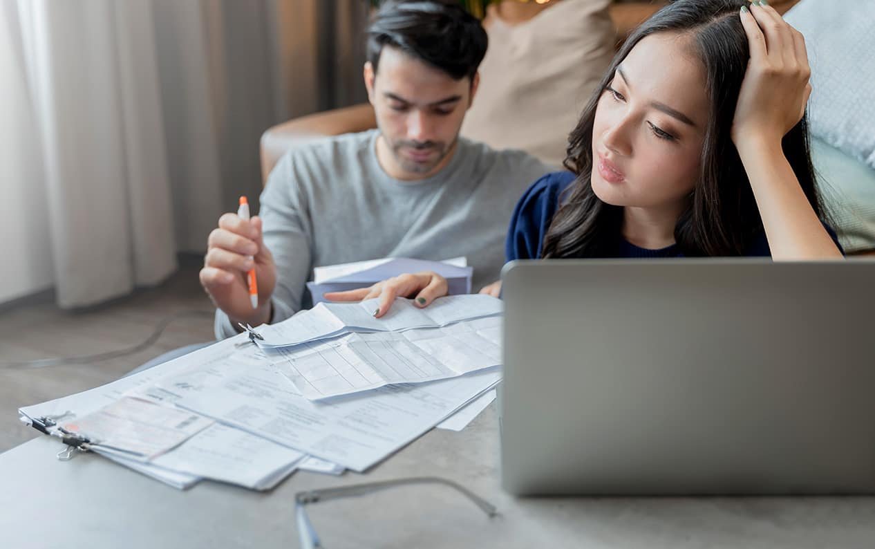 A couple in Ontario appears stressed while reviewing bills and a laptop, possibly related to mortgage concerns or financial strain.