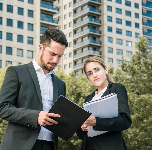 Real estate advisors discussing documents near residential towers, highlighting available incentives and financial benefits for first-time buyers in Ontario.