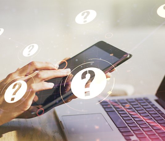 Hands using a tablet with question mark icons floating around, symbolizing frequently asked questions or online inquiry.