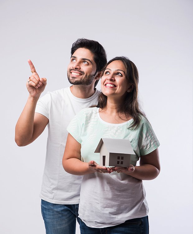 Smiling couple holding house model and pointing upward, representing dreams and questions about home equity loans