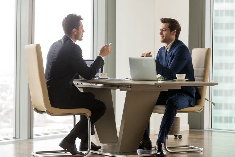 Two men, possibly a mortgage agent and a client in Ontario, are having a personalized consultation at a desk with a laptop.