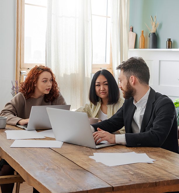 Group of professionals discussing financial documents with laptops at a table, representing consultation about second mortgage options in Ontario.